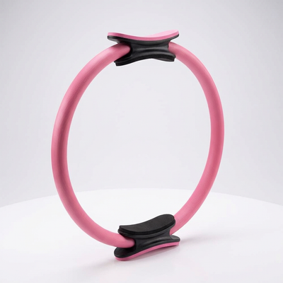 Pink Pilates ring with black handles on a white background